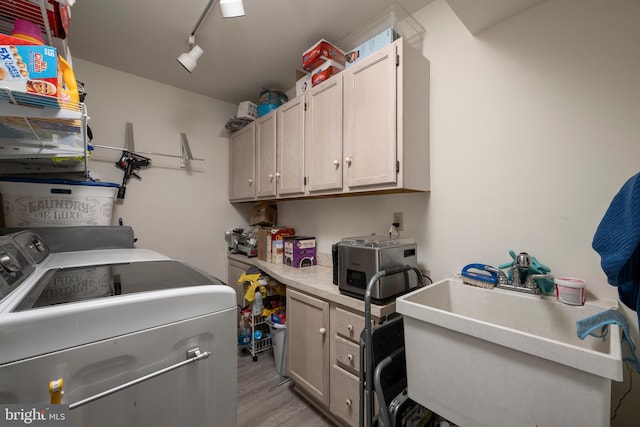 clothes washing area with rail lighting, sink, cabinets, light wood-type flooring, and independent washer and dryer