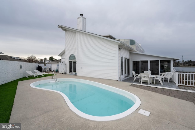 back of property featuring a fenced in pool and a patio