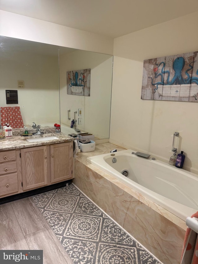 bathroom with tiled tub, vanity, and hardwood / wood-style flooring