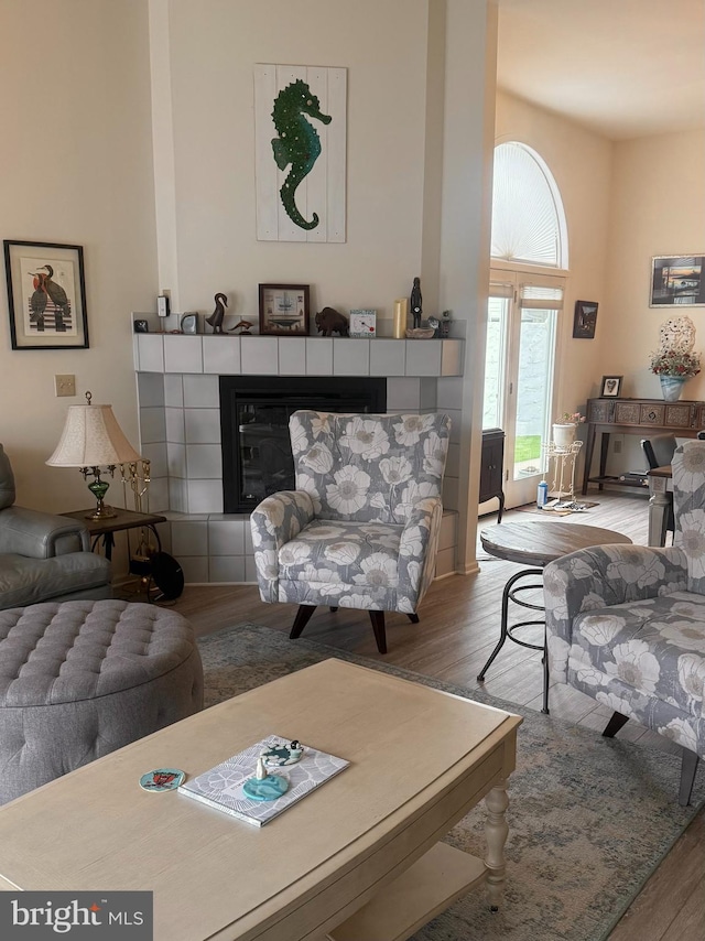 living room featuring a tiled fireplace and hardwood / wood-style flooring