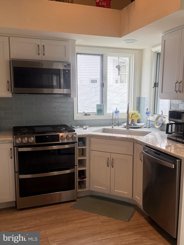 kitchen featuring appliances with stainless steel finishes, sink, white cabinets, and light hardwood / wood-style flooring