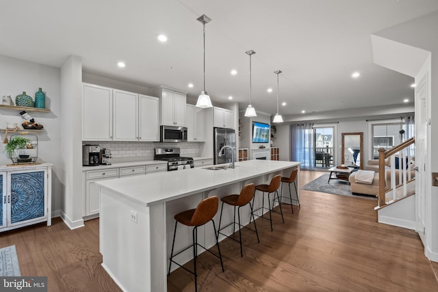 kitchen with decorative light fixtures, stainless steel appliances, an island with sink, and a breakfast bar