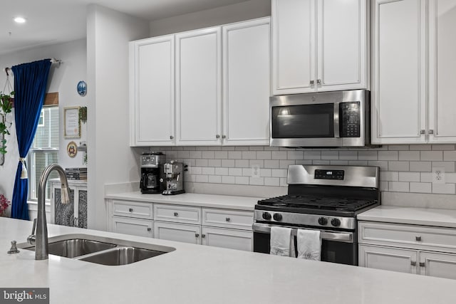 kitchen with white cabinetry, stainless steel appliances, sink, and backsplash