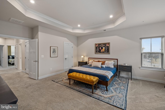 carpeted bedroom with crown molding and a tray ceiling