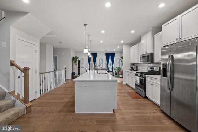 kitchen featuring white cabinetry, appliances with stainless steel finishes, a center island with sink, and pendant lighting