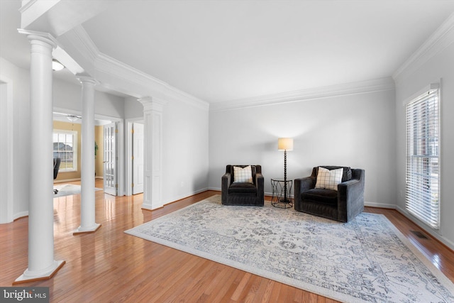 sitting room with decorative columns, ornamental molding, and hardwood / wood-style floors