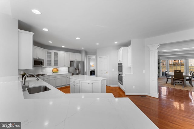 kitchen featuring sink, white cabinetry, a kitchen island, hardwood / wood-style flooring, and stainless steel appliances