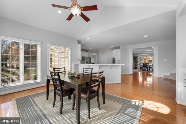 dining area featuring ceiling fan, high vaulted ceiling, light hardwood / wood-style floors, and ornate columns