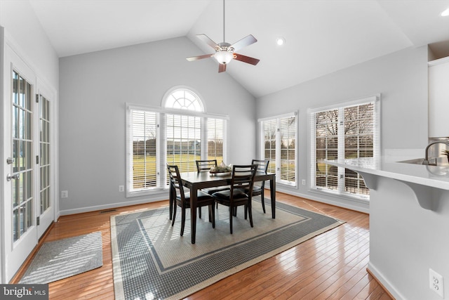 dining room featuring a wealth of natural light, high vaulted ceiling, and light wood-type flooring