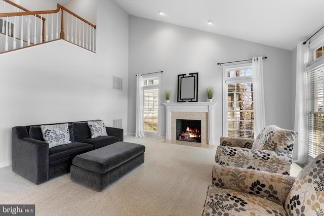 carpeted living room with a high end fireplace and high vaulted ceiling