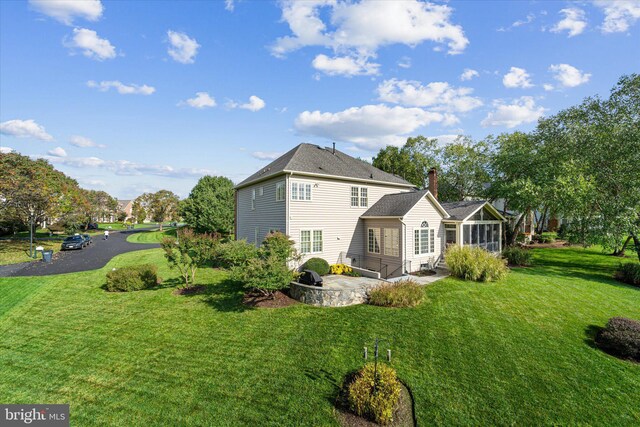 back of house with a sunroom, a yard, and a patio area