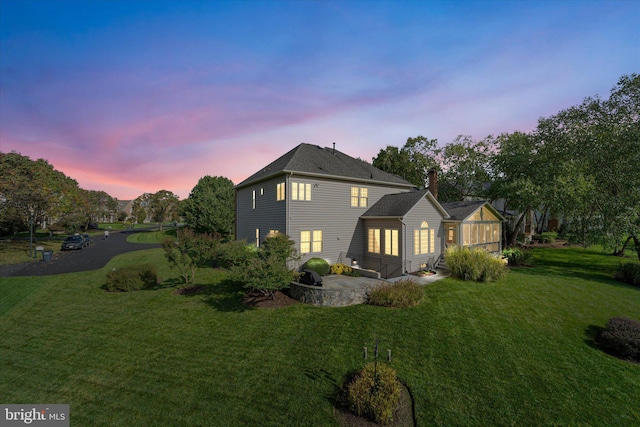 property exterior at dusk with a patio area and a lawn