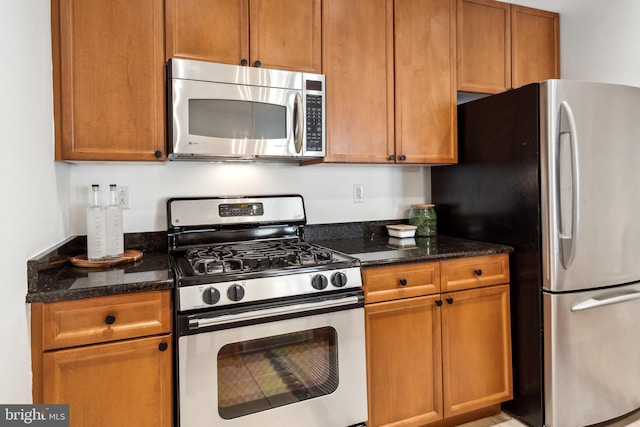 kitchen with appliances with stainless steel finishes and dark stone countertops