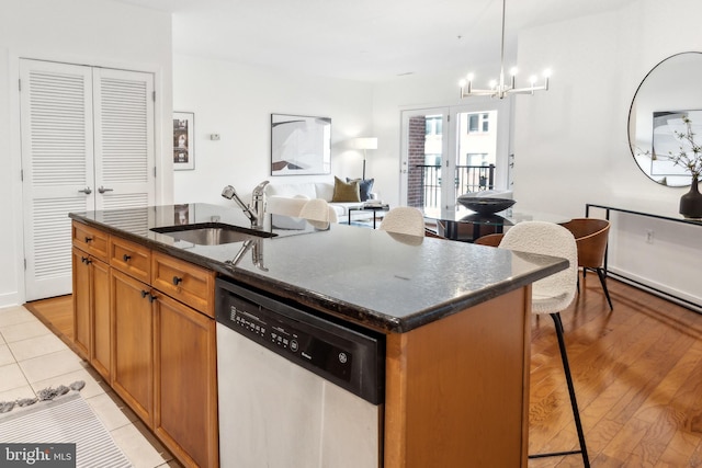 kitchen featuring sink, a breakfast bar area, dishwasher, hanging light fixtures, and an island with sink