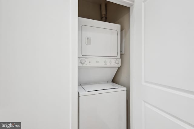 clothes washing area featuring stacked washing maching and dryer