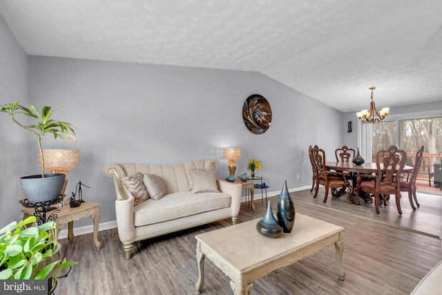 living room featuring an inviting chandelier, vaulted ceiling, wood-type flooring, and a textured ceiling