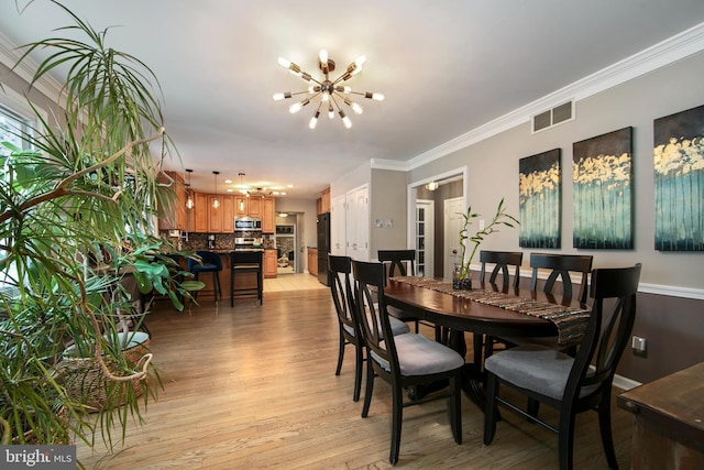 dining area with ornamental molding, light hardwood / wood-style floors, and a notable chandelier