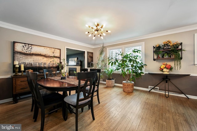 dining area featuring ornamental molding, wood-type flooring, and a fireplace