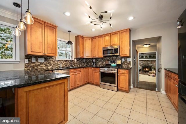 kitchen with stainless steel appliances, tasteful backsplash, pendant lighting, and dark stone counters