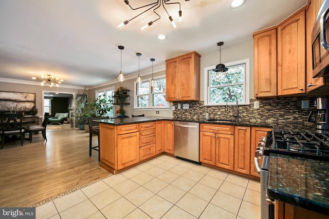 kitchen with appliances with stainless steel finishes, decorative light fixtures, kitchen peninsula, and dark stone counters