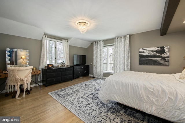 bedroom with hardwood / wood-style floors, lofted ceiling with beams, and multiple windows