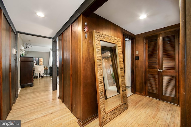 hallway featuring wooden walls and light hardwood / wood-style floors