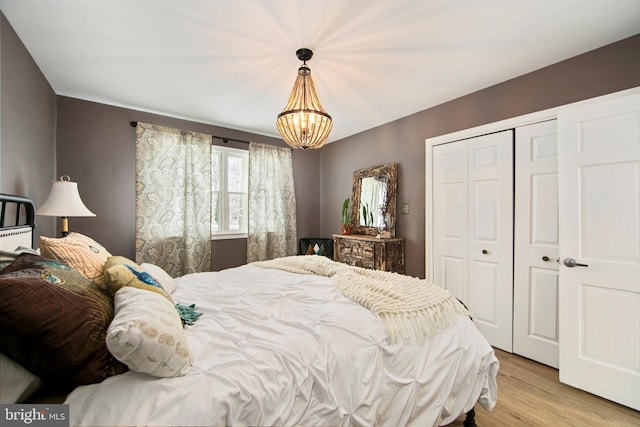 bedroom featuring an inviting chandelier, light wood-type flooring, and a closet