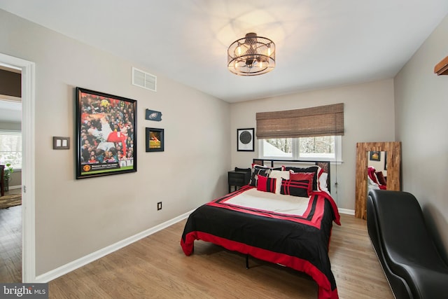 bedroom featuring a chandelier, light hardwood / wood-style floors, and multiple windows