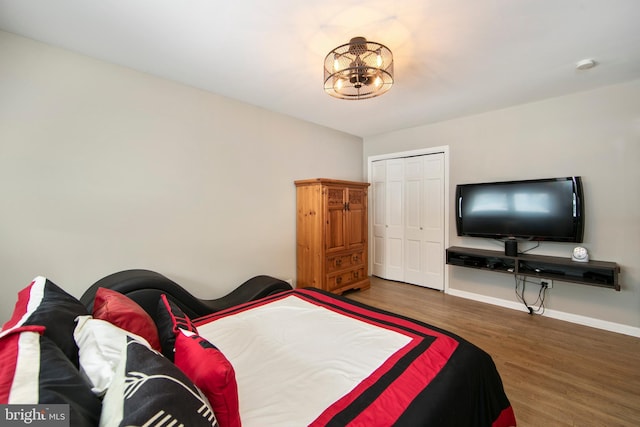 bedroom featuring dark wood-type flooring, a closet, and a notable chandelier