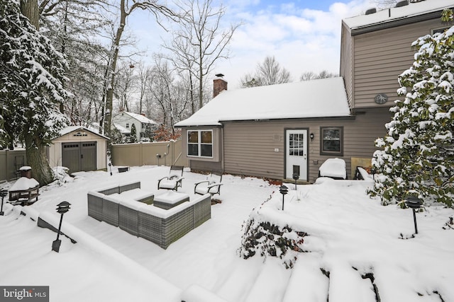 snow covered rear of property with a shed