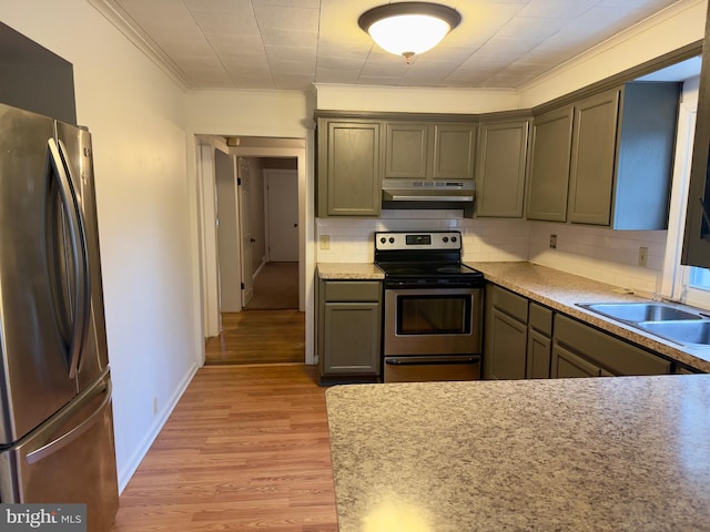 kitchen with appliances with stainless steel finishes, sink, decorative backsplash, crown molding, and light hardwood / wood-style flooring