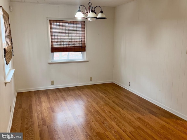 unfurnished room with wood-type flooring and a notable chandelier