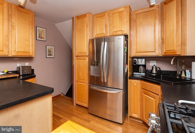 kitchen with lofted ceiling, sink, light hardwood / wood-style flooring, stainless steel appliances, and light brown cabinetry