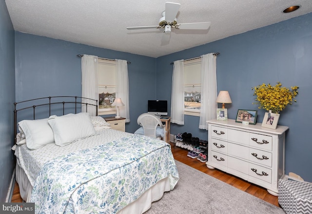 bedroom featuring ceiling fan, dark hardwood / wood-style floors, and a textured ceiling