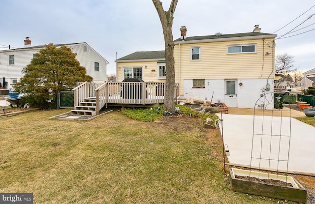 rear view of house featuring a wooden deck and a yard