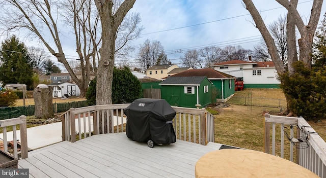 wooden terrace featuring grilling area, a storage shed, and a lawn