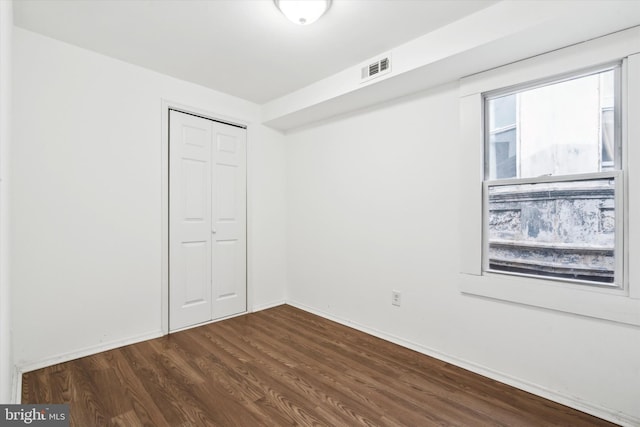 unfurnished bedroom with dark hardwood / wood-style floors and a closet