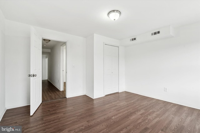 unfurnished bedroom featuring dark hardwood / wood-style flooring and a closet