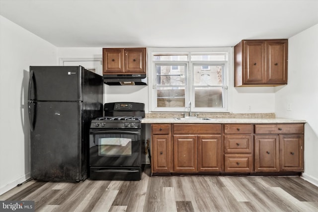 kitchen with sink, light hardwood / wood-style flooring, and black appliances