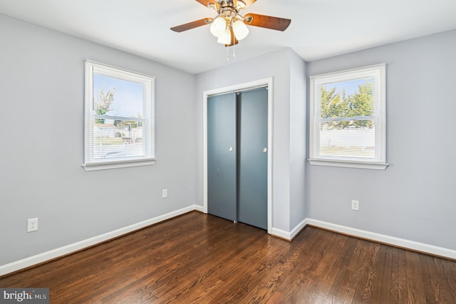 unfurnished bedroom with a ceiling fan, dark wood-style floors, baseboards, and a closet