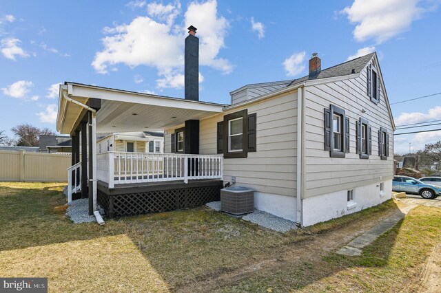 rear view of property featuring a yard, central AC unit, a chimney, and fence