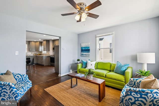 living room featuring ceiling fan, baseboards, and dark wood-style floors