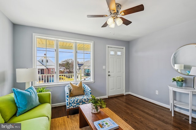 living area featuring visible vents, baseboards, wood finished floors, and a ceiling fan