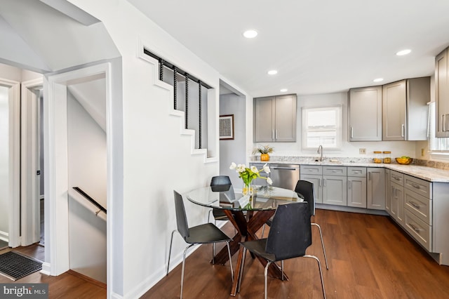 kitchen featuring light stone counters, dark wood-style flooring, a sink, gray cabinetry, and dishwasher