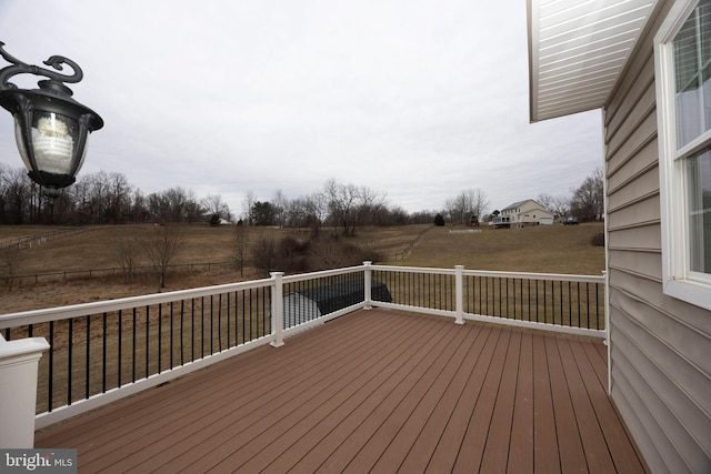 wooden terrace featuring a lawn and a rural view