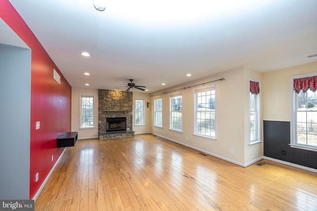 unfurnished living room with ceiling fan, a fireplace, and light hardwood / wood-style floors