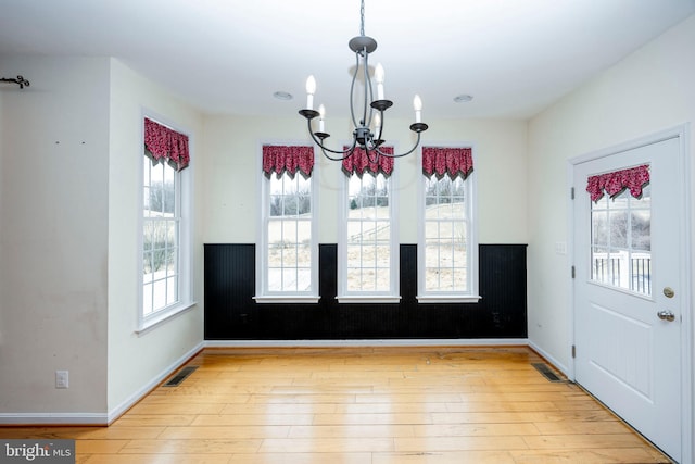 unfurnished dining area with an inviting chandelier and light hardwood / wood-style floors