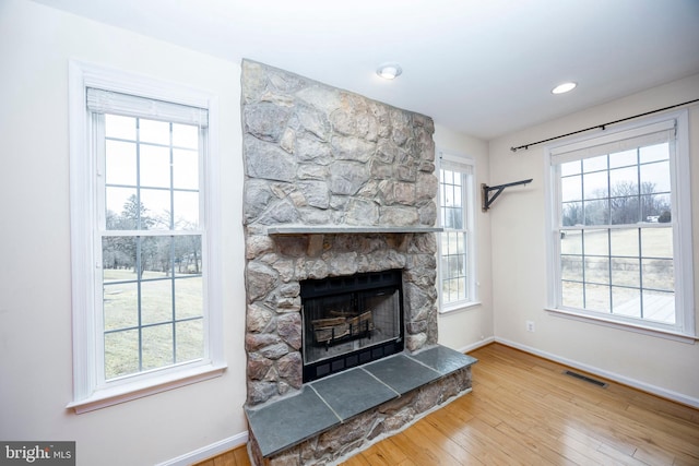 living room with wood-type flooring and a stone fireplace