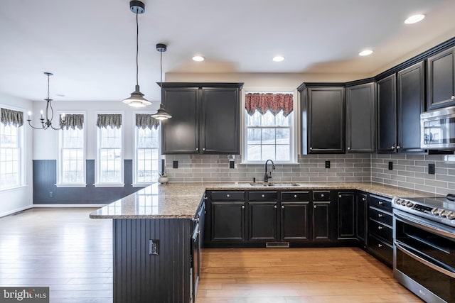 kitchen featuring hanging light fixtures, appliances with stainless steel finishes, sink, and light wood-type flooring