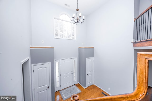 foyer with a towering ceiling, wood-type flooring, and a chandelier